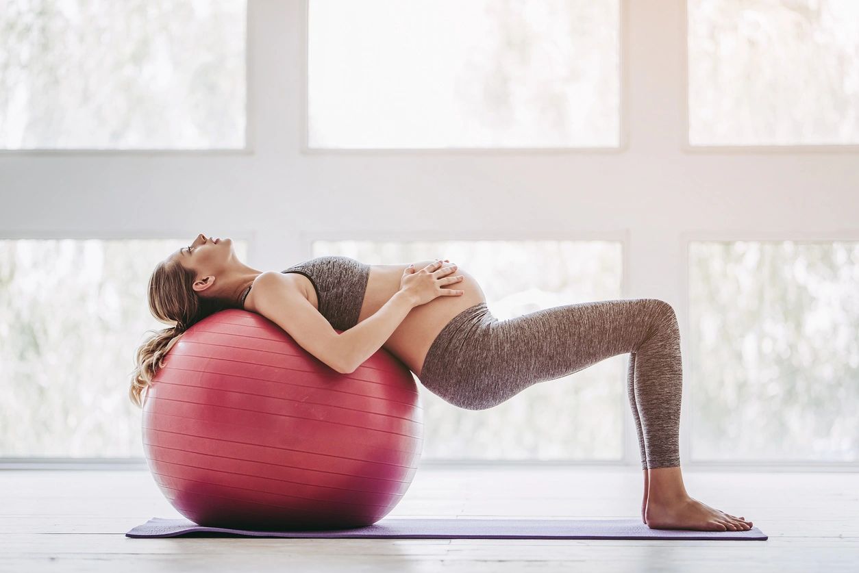 A woman is doing yoga on an exercise ball.