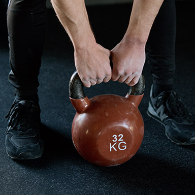 A person is holding onto the handle of a kettlebell.